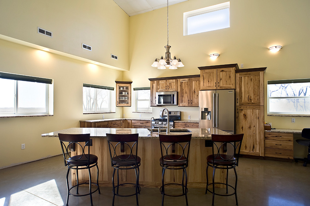 Mid-sized mountain style l-shaped concrete floor and brown floor eat-in kitchen photo with an undermount sink, shaker cabinets, light wood cabinets, granite countertops, stainless steel appliances and an island