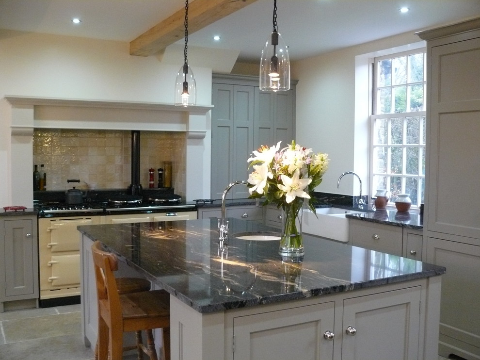 Photo of a mid-sized modern eat-in kitchen in Other with a farmhouse sink, recessed-panel cabinets, granite benchtops, beige splashback, ceramic splashback, limestone floors, with island, white appliances and grey cabinets.