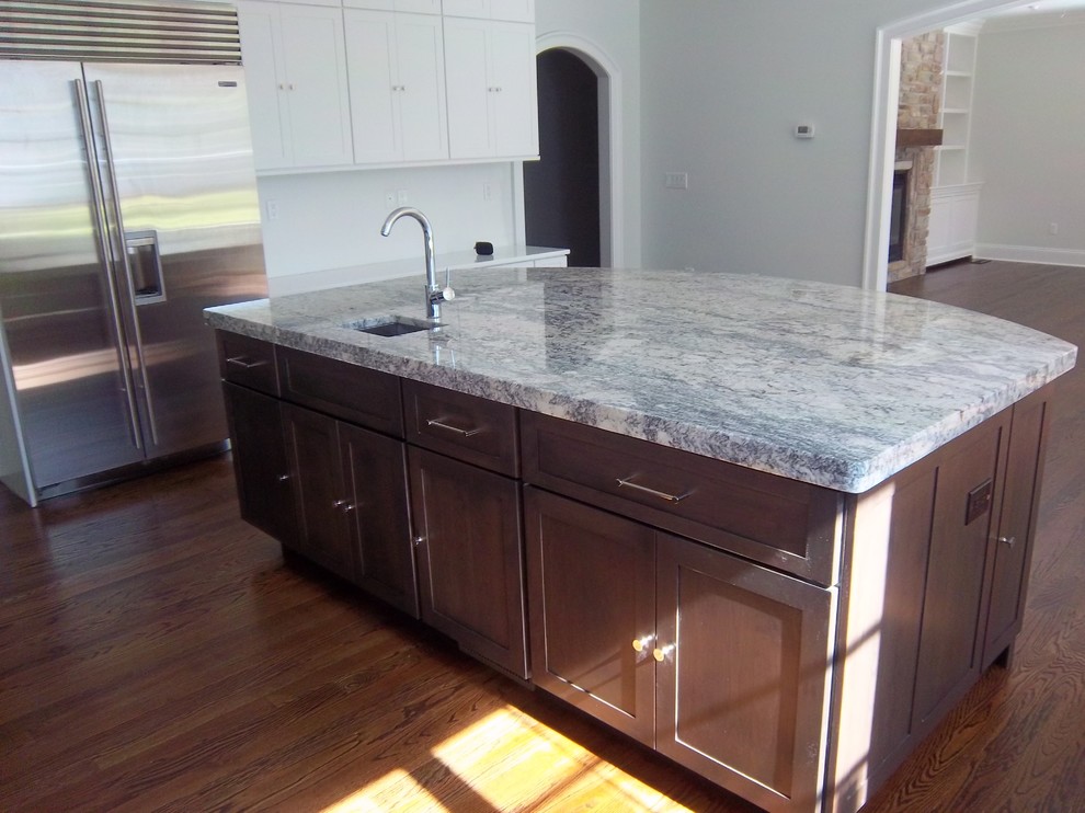 Inspiration for a large transitional u-shaped dark wood floor and brown floor eat-in kitchen remodel with shaker cabinets, white backsplash, stainless steel appliances, an island, an undermount sink, white cabinets, solid surface countertops and white countertops