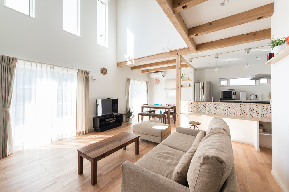 Asian open concept living room in Fukuoka with white walls, medium hardwood floors, a freestanding tv and brown floor.