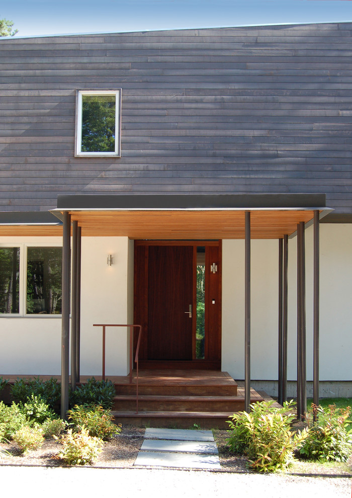 This is an example of a mid-sized contemporary front door in New York with a single front door and a dark wood front door.