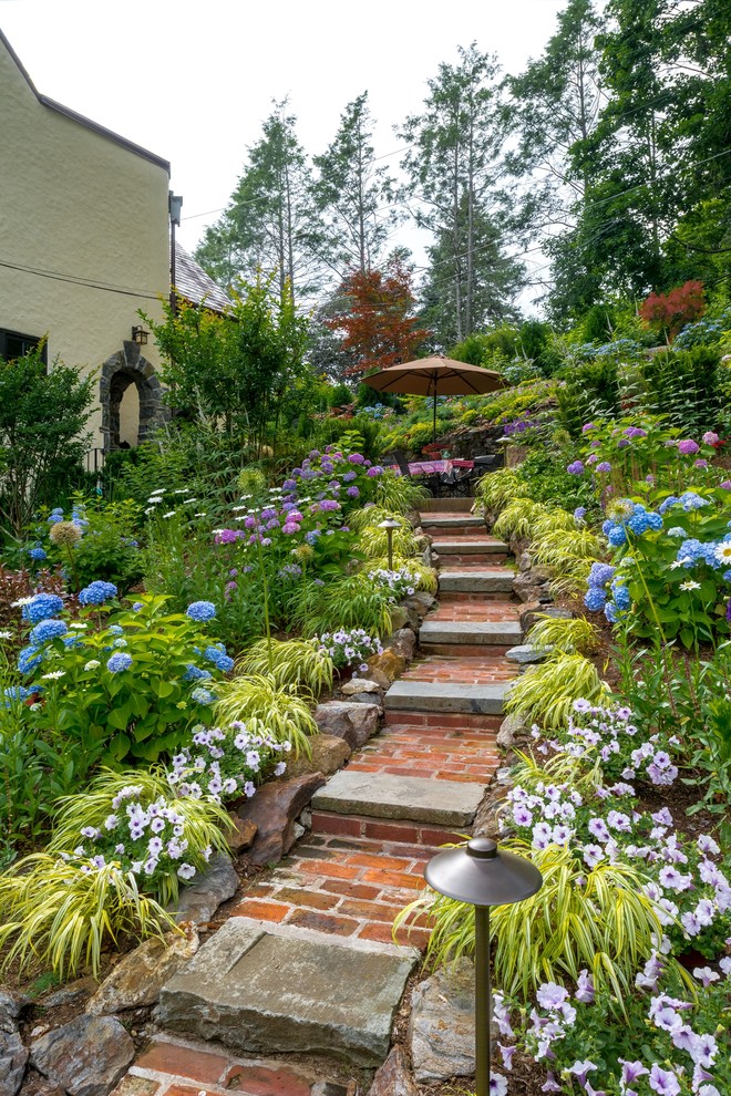 Foto di un ampio giardino classico esposto a mezz'ombra con un pendio, una collina o una riva, pavimentazioni in mattoni e scale