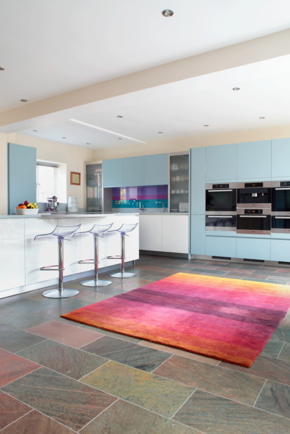 Design ideas for a large contemporary l-shaped eat-in kitchen in Buckinghamshire with flat-panel cabinets, blue cabinets, granite benchtops, blue splashback, glass tile splashback, stainless steel appliances and with island.