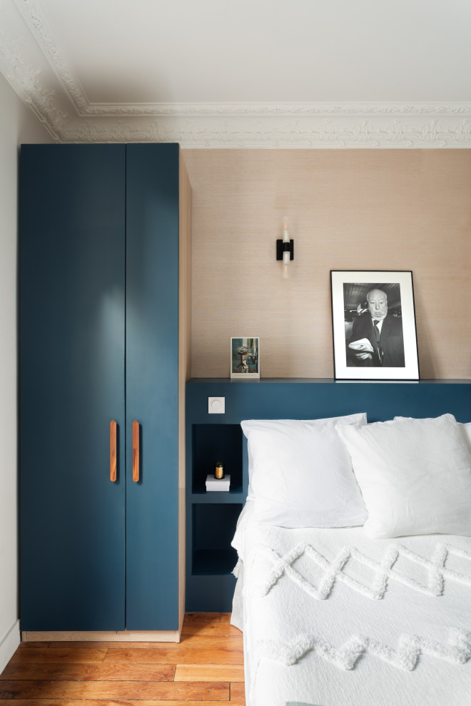 Réalisation d'une chambre parentale haussmannienne minimaliste de taille moyenne avec un mur bleu, un sol en bois brun, une cheminée d'angle, un manteau de cheminée en brique, un plafond en bois et du papier peint.