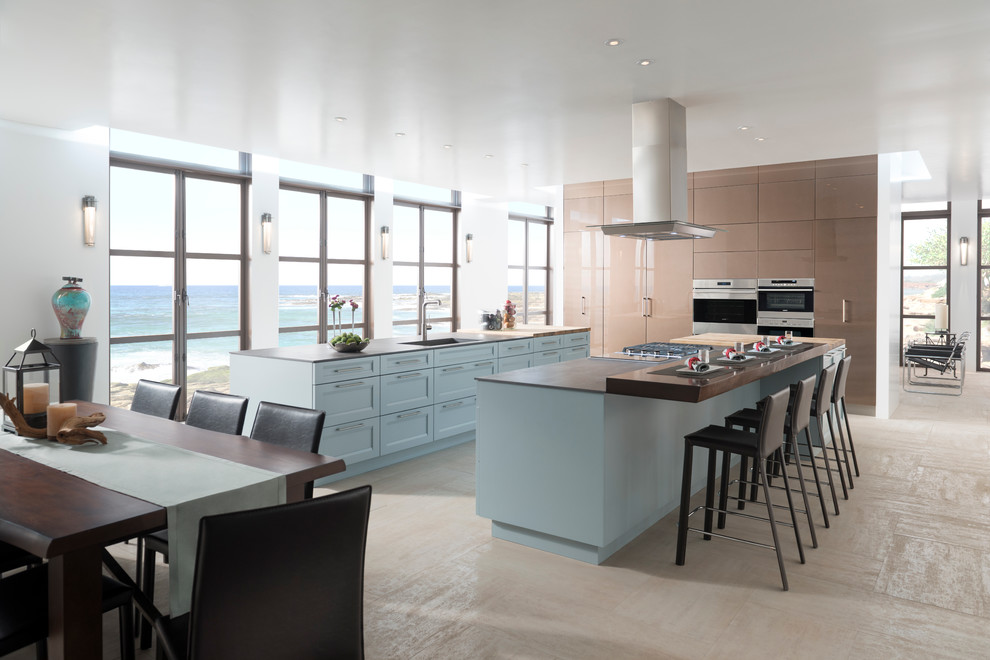 Photo of a beach style u-shaped kitchen in Los Angeles with shaker cabinets, blue cabinets, stainless steel appliances and multiple islands.