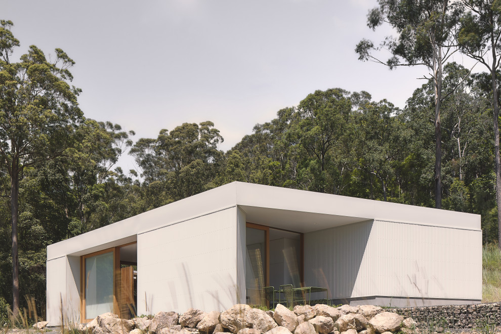 Imagen de fachada de casa blanca y blanca minimalista pequeña de una planta con tejado plano y tejado de metal
