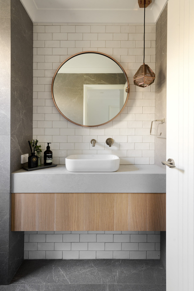 Inspiration for a mid-sized powder room in Perth with furniture-like cabinets, light wood cabinets, a one-piece toilet, white tile, subway tile, white walls, ceramic floors, a vessel sink, engineered quartz benchtops, grey floor, grey benchtops and a floating vanity.