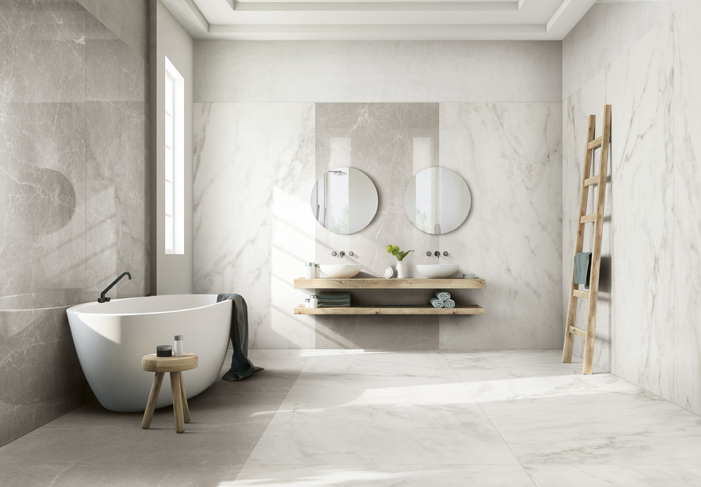 This is an example of a large modern master bathroom in Bologna with light wood cabinets, a freestanding tub, gray tile, porcelain tile, white walls, porcelain floors, a vessel sink, white floor and brown benchtops.