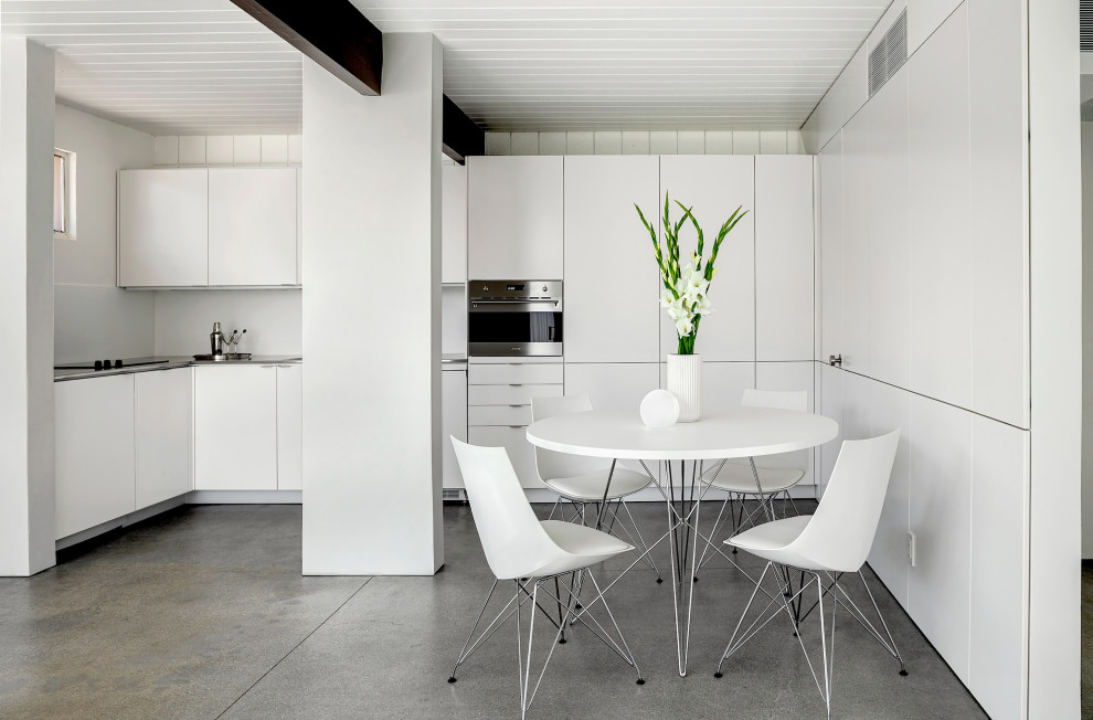 Exempel på ett retro grå grått kök, med en undermonterad diskho, släta luckor, vita skåp, rostfria vitvaror, betonggolv och grått golv