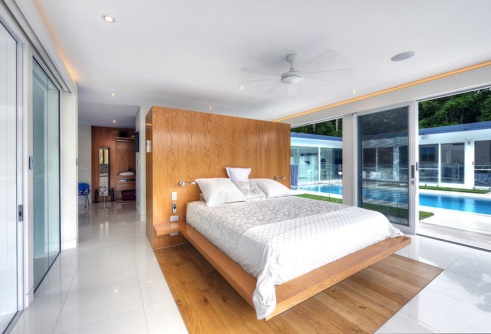 This is an example of a large midcentury master bedroom in Cairns with white walls and porcelain floors.