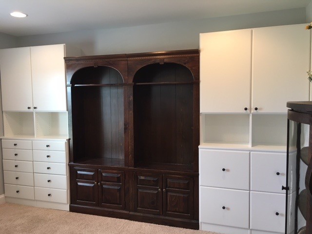 Built in units consisting of different sized drawers. The larger drawers are file drawers for craft paper items. There are cabinets above with adjustable shelving. These are a white melamine flat pane