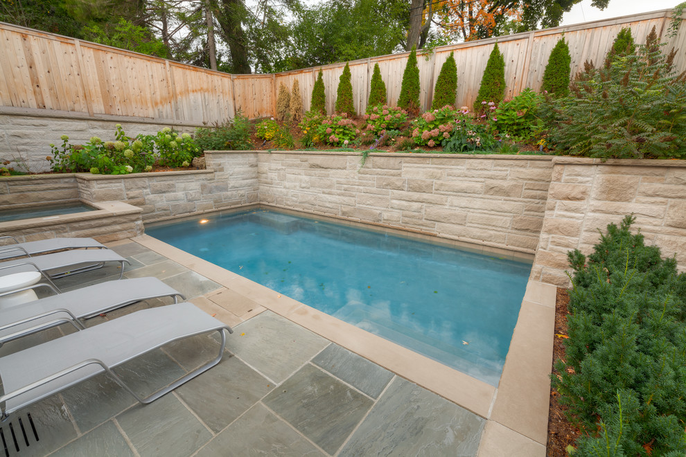 Small traditional backyard rectangular pool in Other with natural stone pavers.