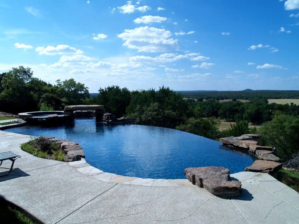 Photo of a mid-sized midcentury side yard custom-shaped aboveground pool in Other with a water feature and stamped concrete.