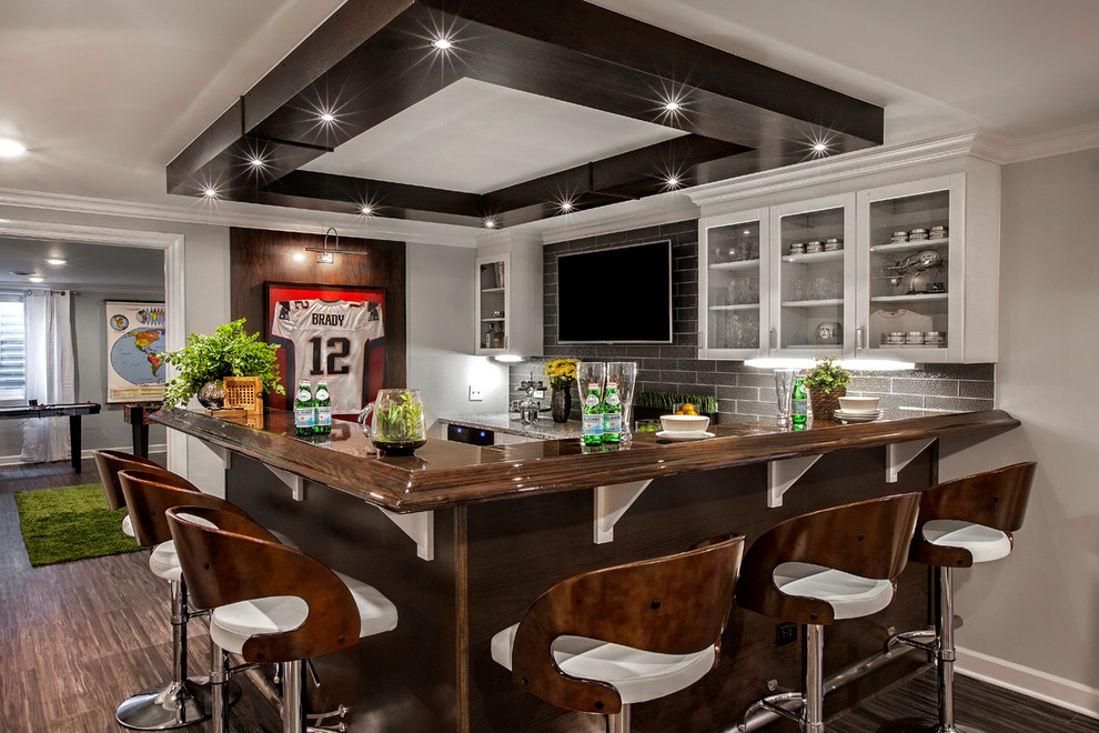 This is an example of a large contemporary l-shaped wet bar in Chicago with glass-front cabinets, white cabinets, wood benchtops, grey splashback, glass tile splashback, bamboo floors and brown floor.