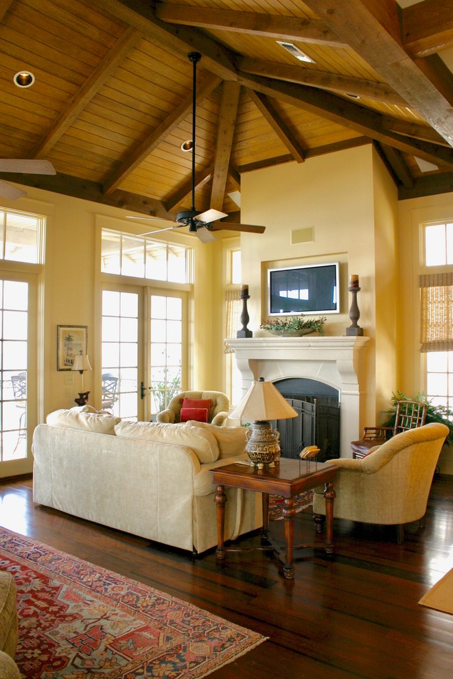 Design ideas for a mid-sized mediterranean formal open concept living room with beige walls, dark hardwood floors, a standard fireplace, a stone fireplace surround, a wall-mounted tv and brown floor.