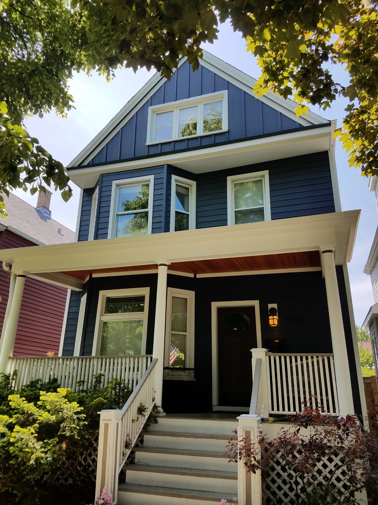 Photo of a mid-sized traditional two-storey blue house exterior in Chicago with concrete fiberboard siding, a gambrel roof and a shingle roof.