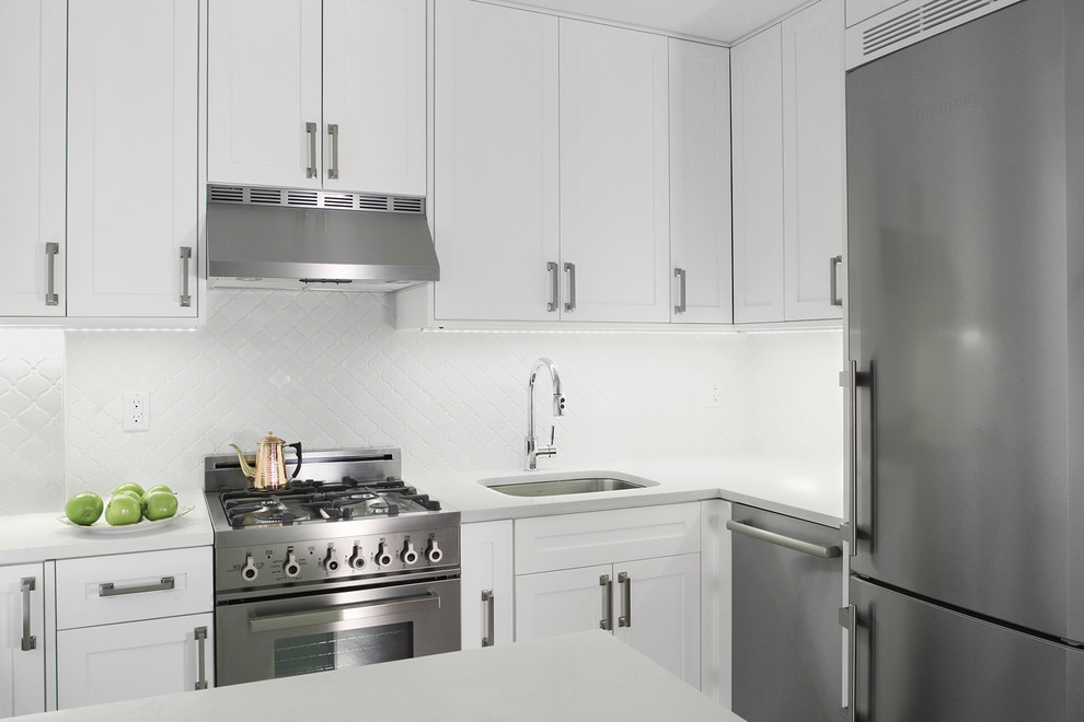 This is an example of a small traditional l-shaped eat-in kitchen in New York with an undermount sink, white cabinets, quartz benchtops, white splashback, subway tile splashback, stainless steel appliances, porcelain floors and shaker cabinets.