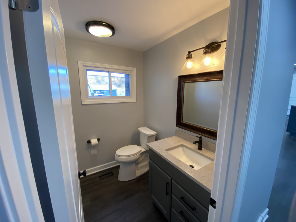 Cette photo montre un petit WC et toilettes moderne avec un placard avec porte à panneau encastré, des portes de placard grises, WC séparés, un mur gris, un sol en vinyl, un lavabo encastré, un plan de toilette en quartz, un sol gris, un plan de toilette beige et meuble-lavabo sur pied.