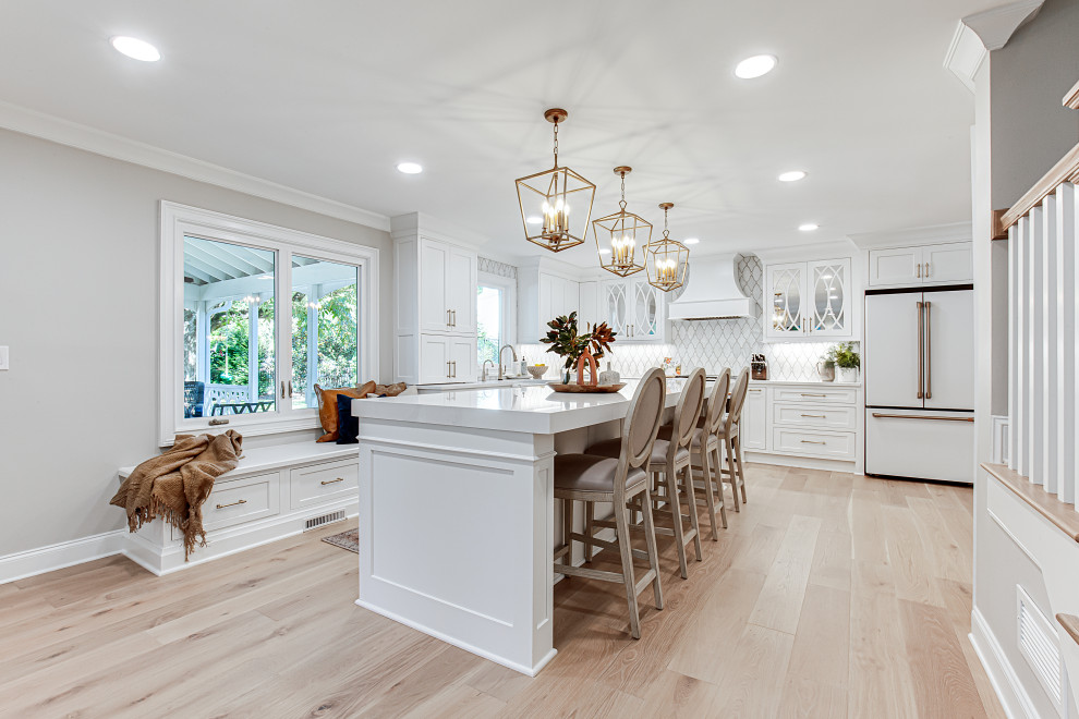 Large elegant l-shaped light wood floor and beige floor open concept kitchen photo in Atlanta with an undermount sink, beaded inset cabinets, white cabinets, quartz countertops, white backsplash, marble backsplash, white appliances, an island and white countertops