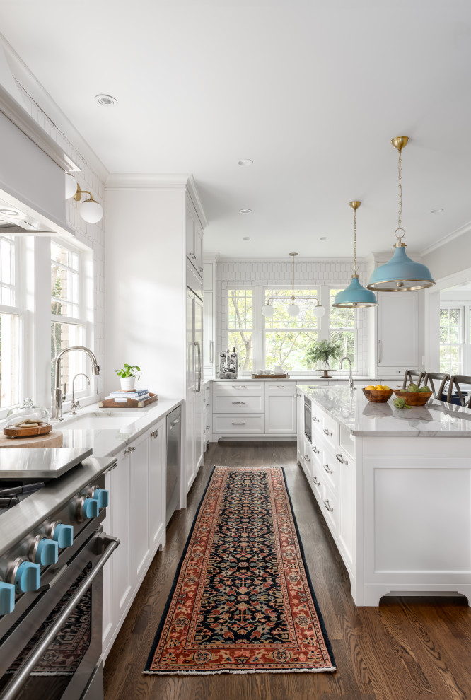 Large beach style galley eat-in kitchen in Atlanta with an undermount sink, shaker cabinets, white cabinets, quartzite benchtops, white splashback, marble splashback, panelled appliances, dark hardwood floors, with island, brown floor and white benchtop.