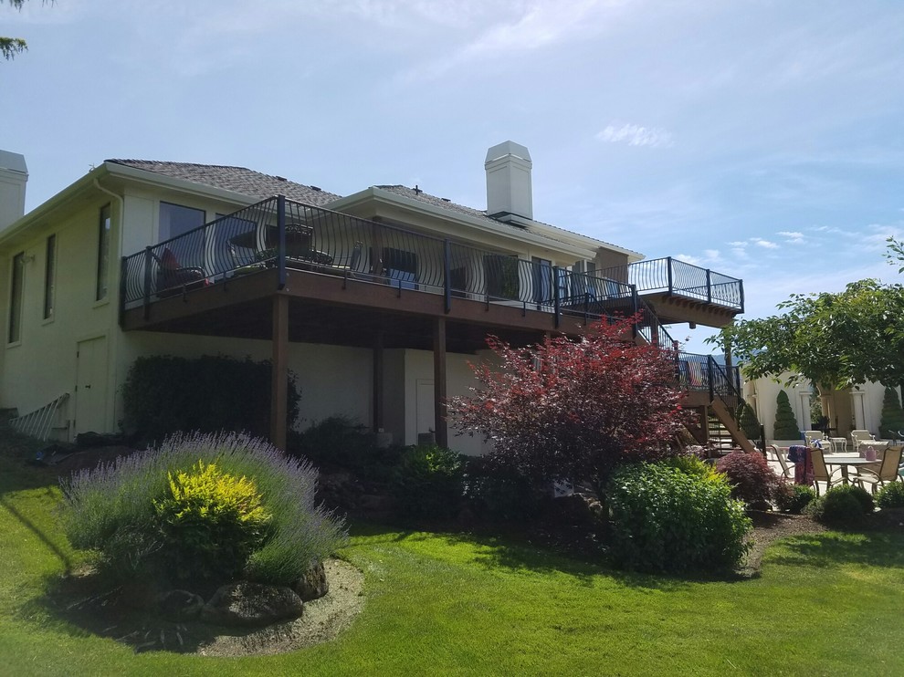 Example of a huge transitional backyard deck design with a fire pit and a roof extension