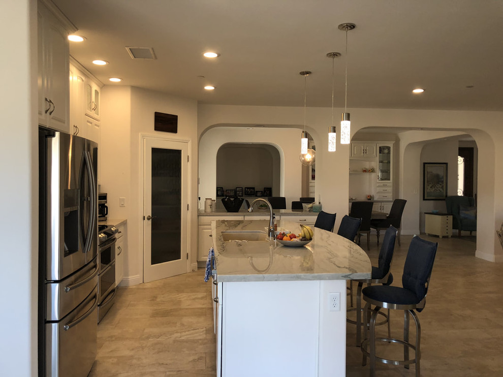 This is an example of a mid-sized contemporary l-shaped open plan kitchen in Los Angeles with an undermount sink, raised-panel cabinets, white cabinets, marble benchtops, multi-coloured splashback, matchstick tile splashback, stainless steel appliances, porcelain floors, with island, beige floor and multi-coloured benchtop.
