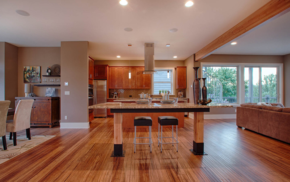 This is an example of a large contemporary galley open plan kitchen in Seattle with an undermount sink, shaker cabinets, medium wood cabinets, granite benchtops, brown splashback, glass tile splashback, stainless steel appliances, bamboo floors, multiple islands and beige floor.