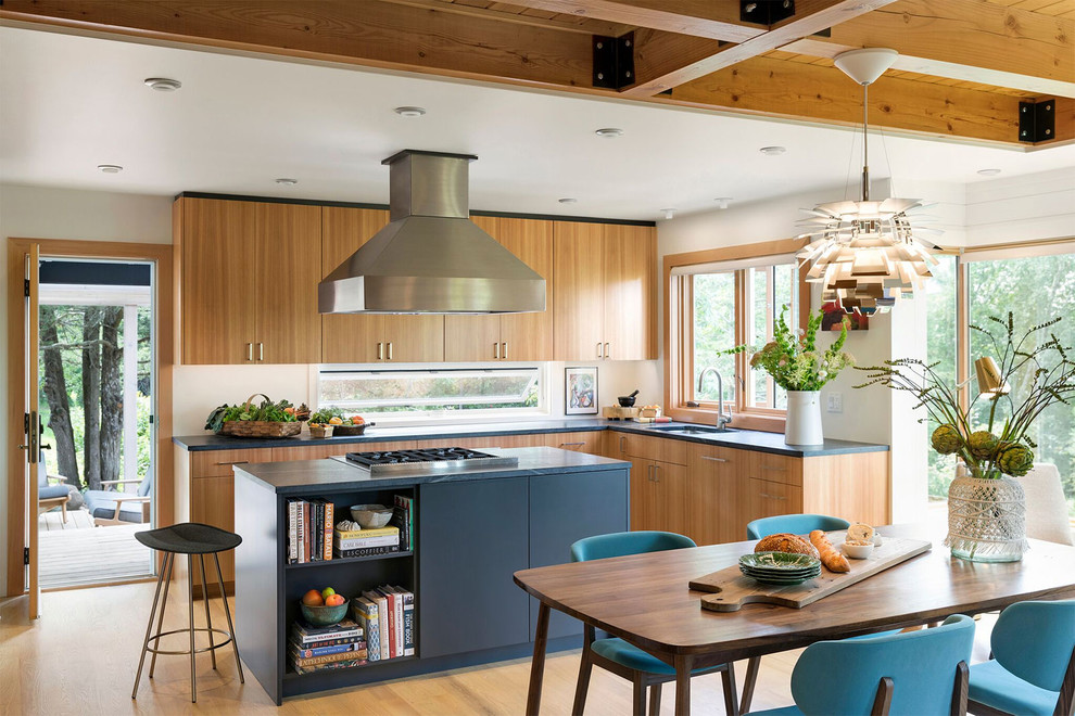 Inspiration for a midcentury l-shaped eat-in kitchen in Minneapolis with an undermount sink, flat-panel cabinets, light wood cabinets, window splashback, with island, black benchtop and light hardwood floors.