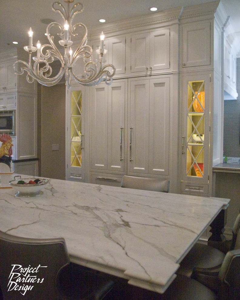 This is an example of a traditional u-shaped eat-in kitchen in San Francisco with an undermount sink, beaded inset cabinets, white cabinets, marble benchtops, white splashback and stainless steel appliances.