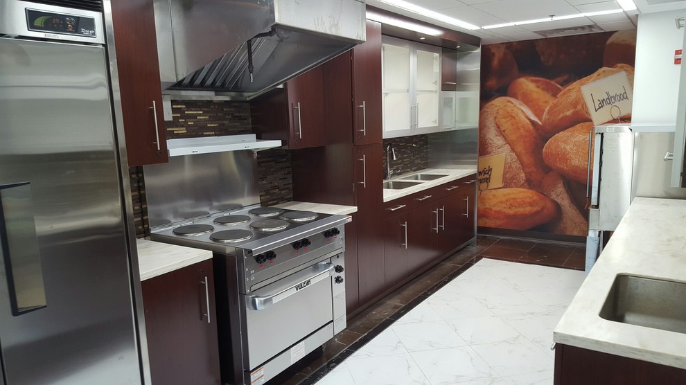 Photo of a mid-sized contemporary galley eat-in kitchen in New York with a double-bowl sink, flat-panel cabinets, dark wood cabinets, solid surface benchtops, brown splashback, mosaic tile splashback, stainless steel appliances, porcelain floors and no island.