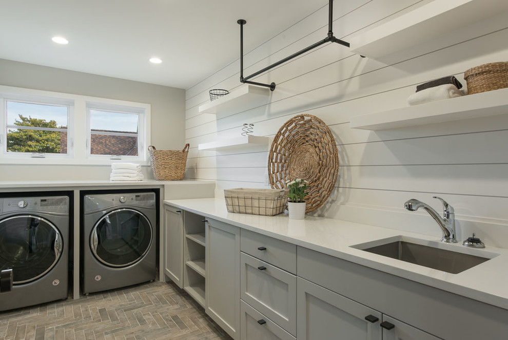 Inspiration for a mid-sized contemporary l-shaped dedicated laundry room in Seattle with an undermount sink, shaker cabinets, grey cabinets, solid surface benchtops, white walls, brick floors, a side-by-side washer and dryer and red floor.