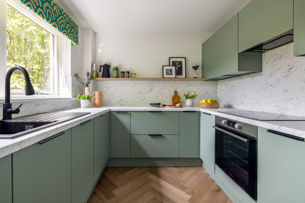 Photo of a contemporary u-shaped kitchen in Glasgow with a built-in sink, flat-panel cabinets, green cabinets, white splashback, stone slab splashback, stainless steel appliances, medium hardwood flooring, no island, brown floors and white worktops.