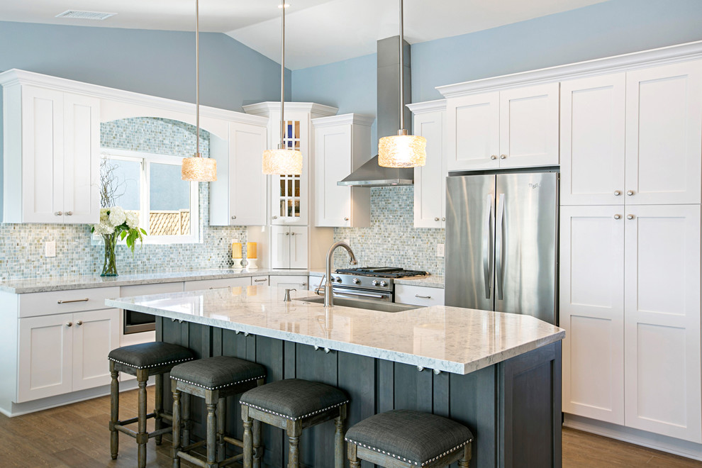 Design ideas for a large beach style kitchen in San Diego with a farmhouse sink, recessed-panel cabinets, dark wood cabinets, quartz benchtops, blue splashback, glass tile splashback, stainless steel appliances, ceramic floors and with island.