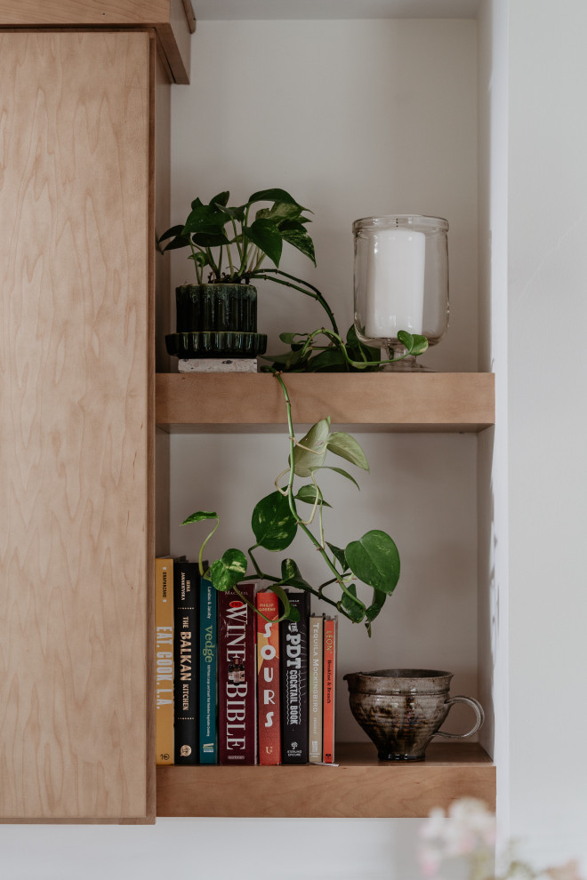 Inspiration for a mid-sized mid-century modern l-shaped medium tone wood floor kitchen pantry remodel in Detroit with an undermount sink, flat-panel cabinets, light wood cabinets, quartz countertops, white backsplash, quartz backsplash, stainless steel appliances, a peninsula and white countertops