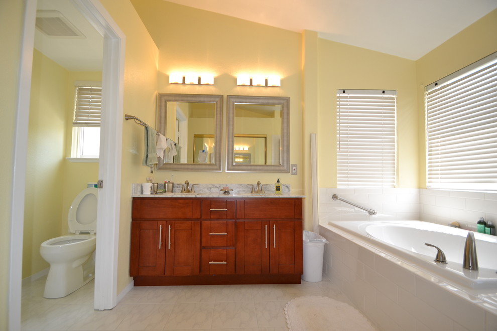 Inspiration for a large traditional master bathroom in San Francisco with a drop-in sink, shaker cabinets, brown cabinets, marble benchtops, a corner shower, a one-piece toilet, white tile, ceramic tile, yellow walls and ceramic floors.