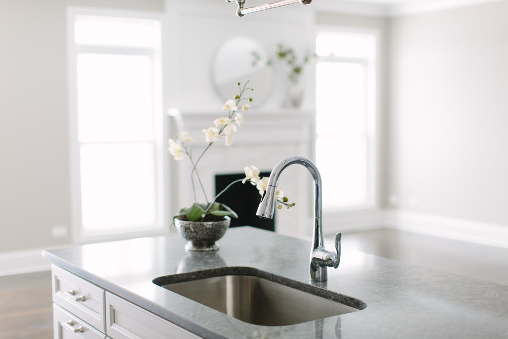Inspiration for a mid-sized transitional dark wood floor eat-in kitchen remodel in Chicago with a single-bowl sink, shaker cabinets, white cabinets, granite countertops, black backsplash, glass tile backsplash, stainless steel appliances and an island