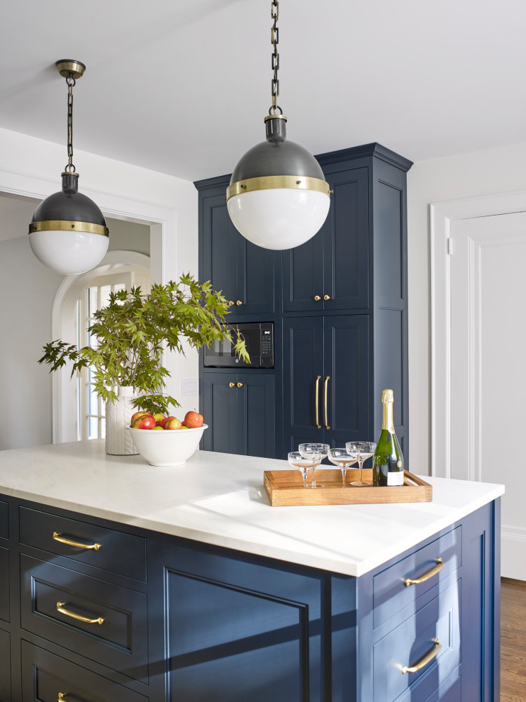 Design ideas for a small transitional u-shaped eat-in kitchen in New York with a triple-bowl sink, shaker cabinets, blue cabinets, marble benchtops, white splashback, ceramic splashback, stainless steel appliances, dark hardwood floors, with island, brown floor and white benchtop.
