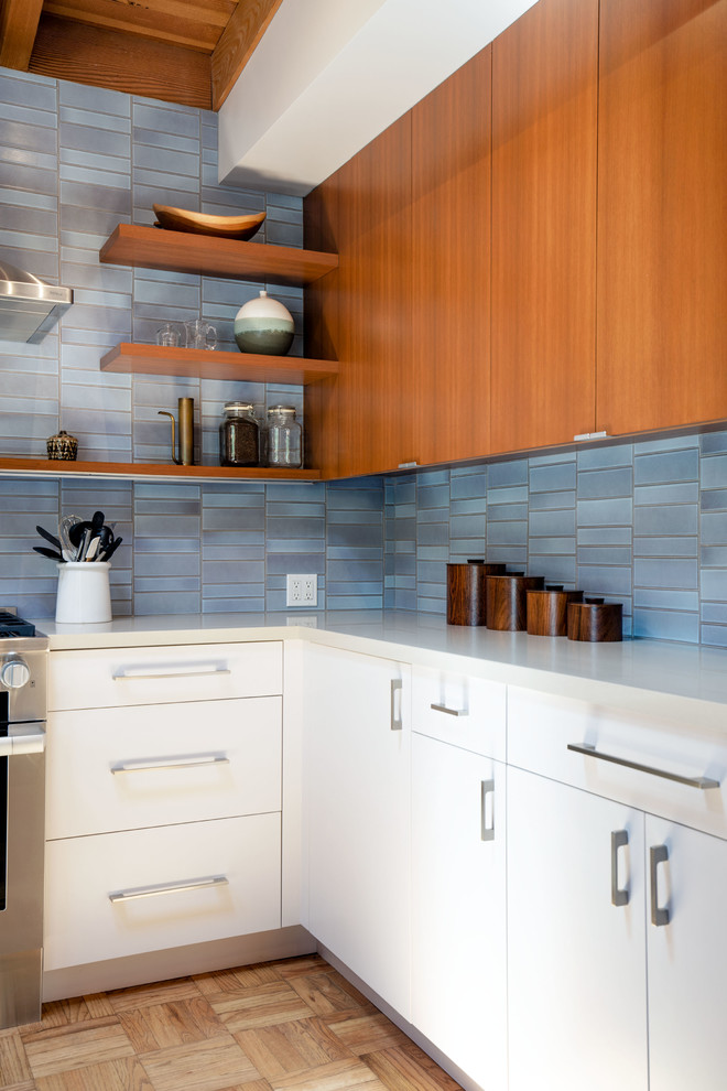 Photo of a large midcentury l-shaped open plan kitchen in Los Angeles with an undermount sink, flat-panel cabinets, medium wood cabinets, quartz benchtops, blue splashback, ceramic splashback, stainless steel appliances, light hardwood floors, with island and grey benchtop.