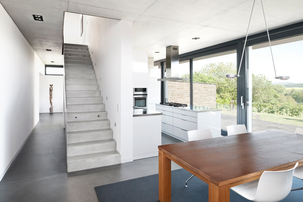 This is an example of a mid-sized contemporary open plan dining in Nuremberg with white walls and concrete floors.