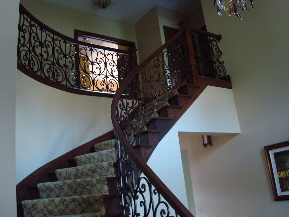 Photo of a mid-sized traditional carpeted curved staircase in Other with carpet risers and wood railing.