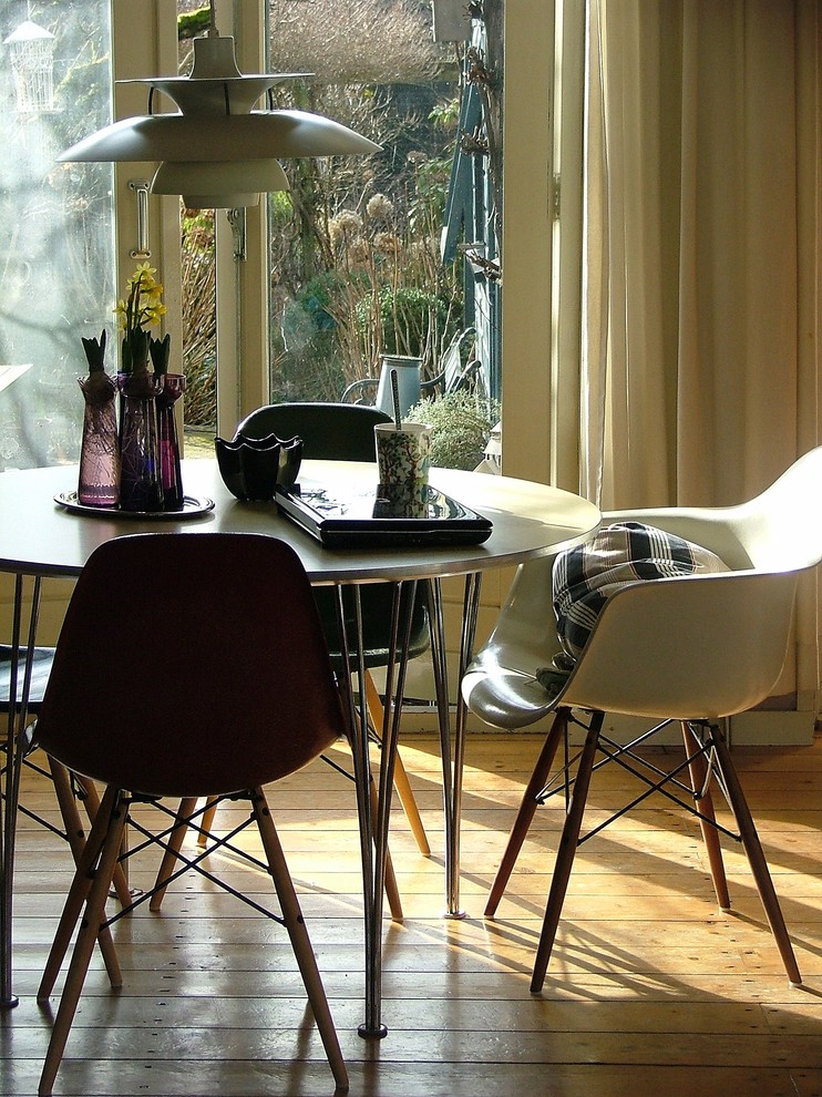 This is an example of a midcentury dining room in Amsterdam with medium hardwood floors.