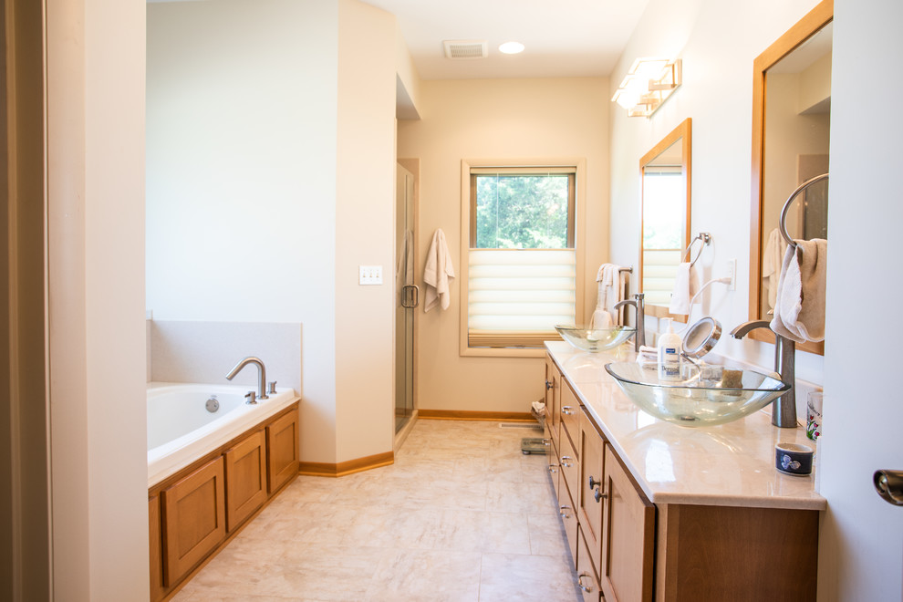 Photo of a mid-sized transitional master bathroom in Other with shaker cabinets, medium wood cabinets, a drop-in tub, a corner shower, white walls, ceramic floors, a vessel sink, beige floor, a hinged shower door and beige benchtops.
