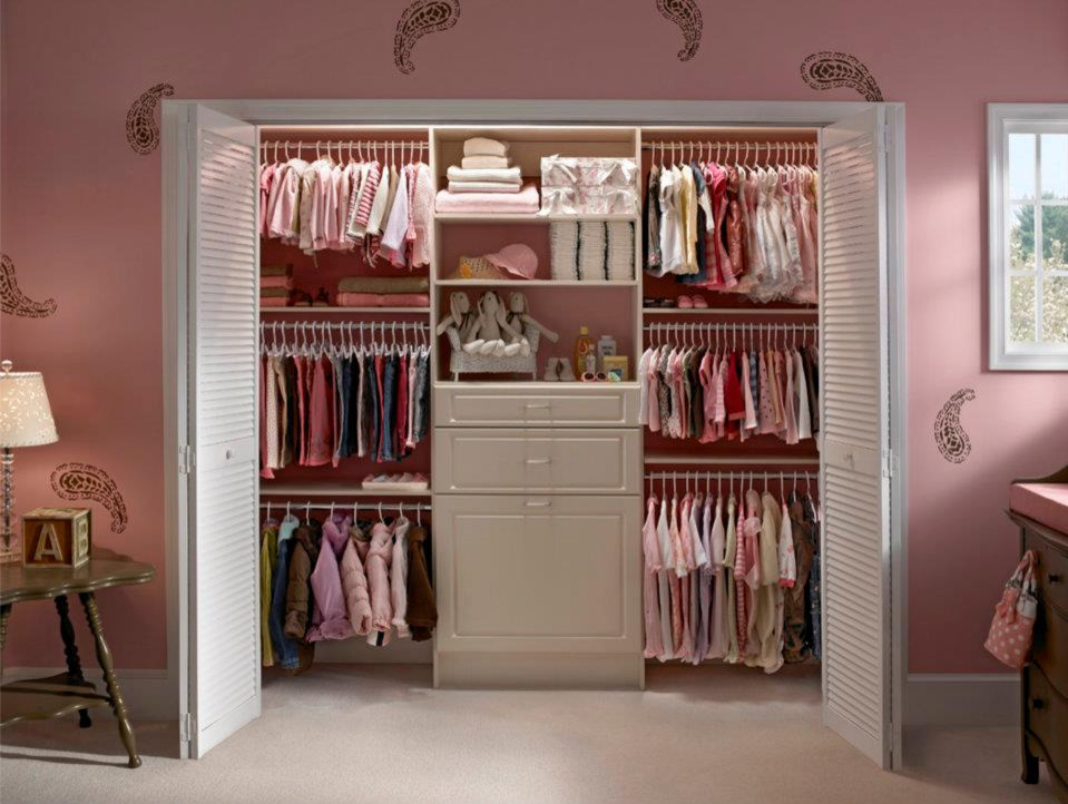 This is an example of a mid-sized eclectic women's built-in wardrobe in Toronto with flat-panel cabinets, white cabinets, carpet and beige floor.