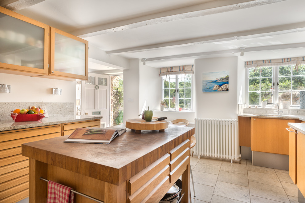 This is an example of a mid-sized kitchen in Devon with flat-panel cabinets, light wood cabinets, granite benchtops, white splashback, ceramic splashback, coloured appliances, ceramic floors and with island.
