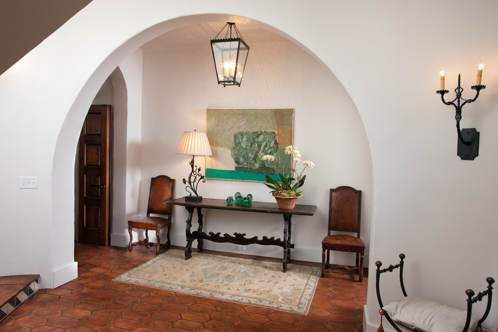 Inspiration for a mediterranean entryway in Other with white walls and terra-cotta floors.