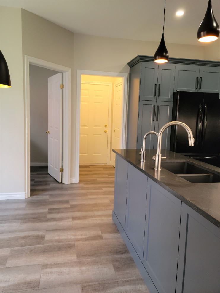 Example of a mid-sized transitional u-shaped vinyl floor eat-in kitchen design with an undermount sink, recessed-panel cabinets, blue cabinets, quartzite countertops, white backsplash, porcelain backsplash, black appliances, a peninsula and black countertops