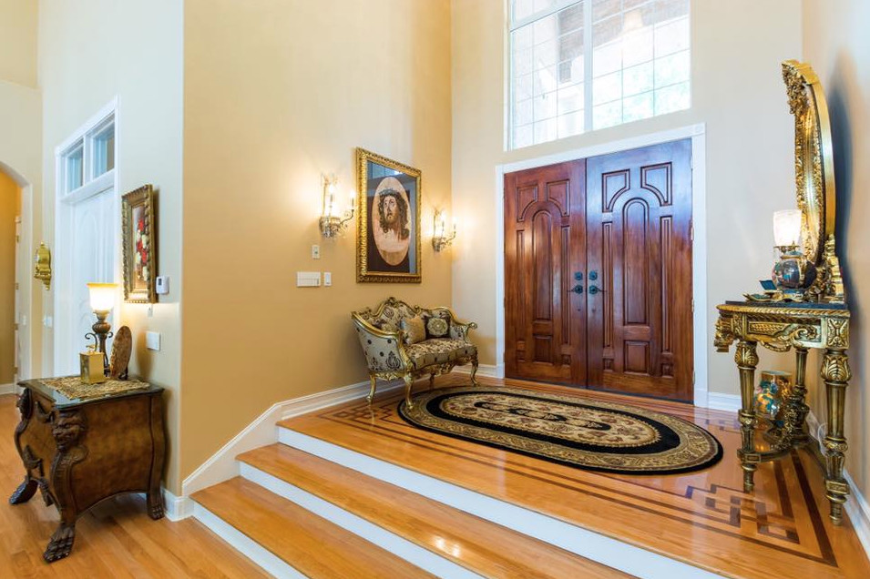 Design ideas for a large traditional foyer in Tampa with yellow walls, medium hardwood floors, a double front door, a dark wood front door and brown floor.