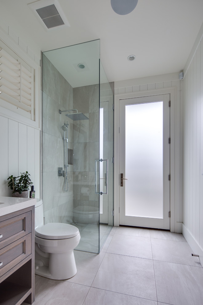 Design ideas for a beach style bathroom in Vancouver with dark wood cabinets, a curbless shower, white walls, grey floor, a hinged shower door, white benchtops and recessed-panel cabinets.
