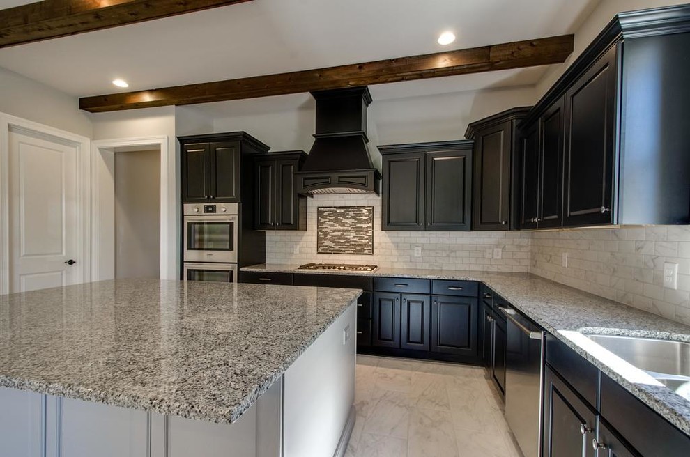 Example of a mid-sized transitional l-shaped ceramic tile and white floor open concept kitchen design with an undermount sink, raised-panel cabinets, brown cabinets, granite countertops, white backsplash, ceramic backsplash, stainless steel appliances and an island