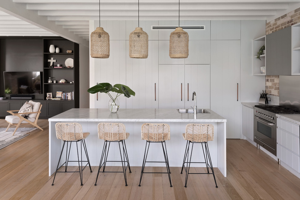 Inspiration for a mid-sized beach style open plan kitchen in Sydney with light hardwood floors.